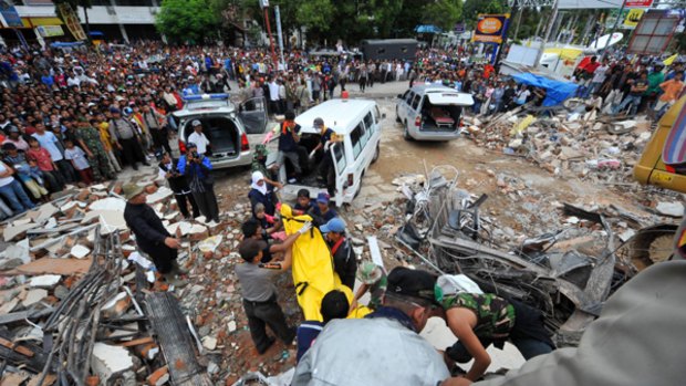 Indonesian rescuers search through the rubble of a colapsed building in Padang.