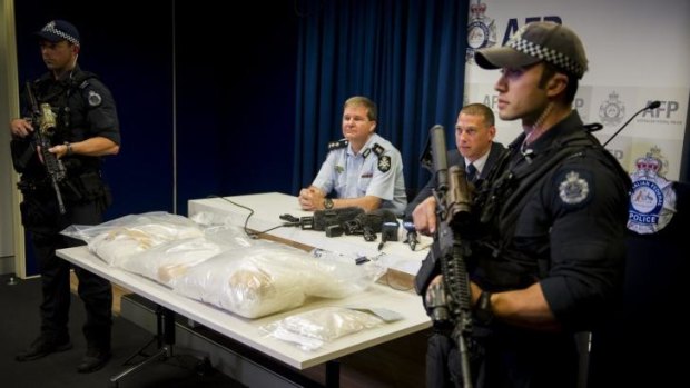 Acting Commander Paul Shakeshaft and Detective Sergeant Shane Scott address the media while armed police guard the drugs.