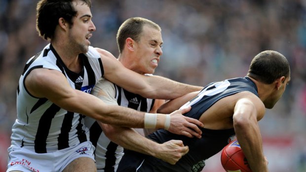 Collingwood's Steele Sidebottom and Nick Maxwell tackle Carlton's Chris Yarran. Picture Sebastian Costanzo.