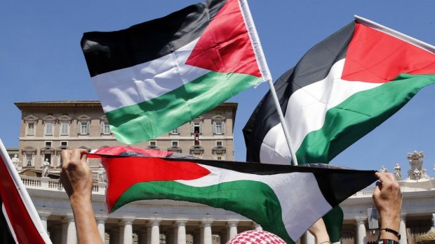 Praying for peace: People wave Palestinian flags as Pope Francis delivers prayers in Saint Peter's Square on Sunday.