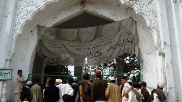 People in Buner, Pakistan, stand at an entrance of a shrine to the  Sufi saint Pir Baba, closed by Taliban activists.