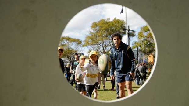 Matt Toomua gives some tips to the kids at a Wallabies fan day in Circular Quay on Thursday.