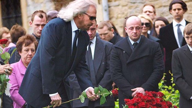 Barry Gibb places a red rose on his brother Robin's grave during the burial service in the churchyard in Thame, England.