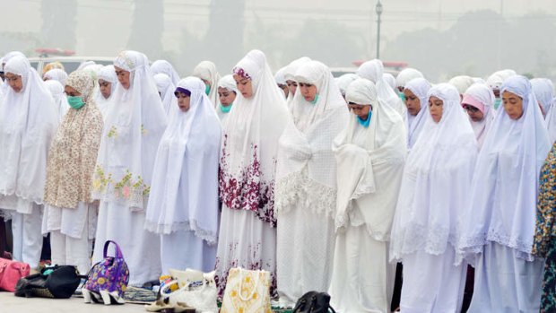 Indonesian Muslim women take part in mass prayers asking for rain at a square covered by thick haze in Dumai.