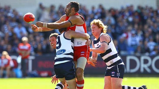 Sydney's Adam Goodes gets a handball away as he is tackled by Geelong's James Kelly at Skilled Stadium.