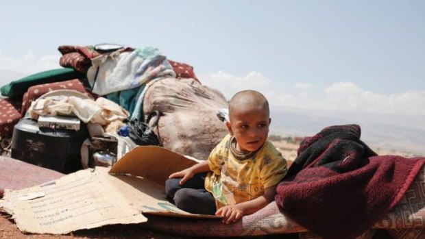 No place to hide: Youssef Akkash, 3, from Aleppo sits among his family's belongings in a makeshift refugee settlement in Ayyat, Lebanon, last year.