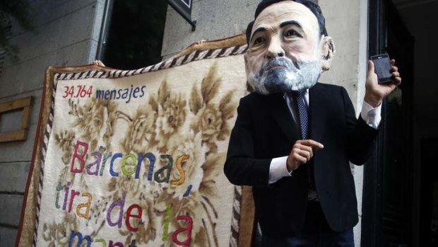A protester wearing a mask depicting Spanish Prime Minister Mariano Rajoy demonstrates outside Madrd's High Court.