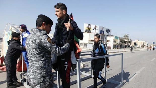 Iraqi policemen search Shi'ite pilgrims as they walk to the holy city of Kerbala.