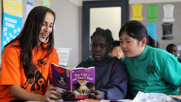 Antonia Horafiaris, 15, of East Malvern, reads yesterday to Veronica Dador, 9, and Kelly Huynh at Sacred Heart Primary School in Fitzroy.