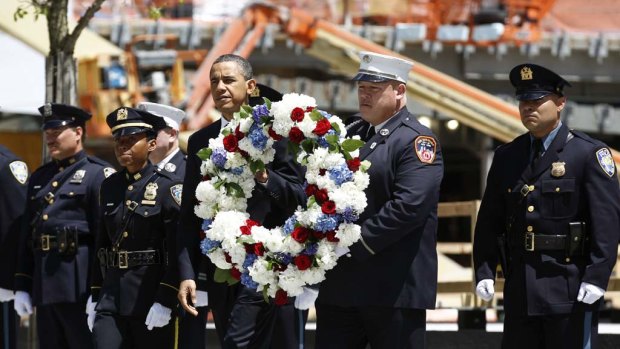 US President Barack Obama carries a wreath accompanied by New York City firefighters and NYPD police officers during a wreath laying ceremony at the National September 11th Memorial at the World Trade Centre.
