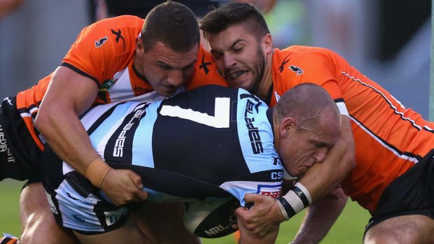Cronulla halfback Jeff Robson is crunched by the defence during the NRL trial against the Wests Tigers at Remondis Stadium.