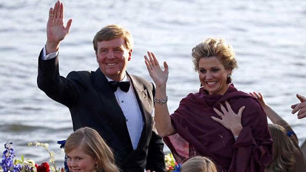 Dutch King Willem-Alexander and Queen Maxima wave during a boat parade in Amsterdam.