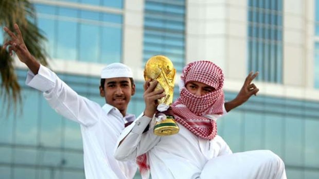 True fan . . .Qatari youths hold a mock World Cup trophy inm celebration after their country won the 2022 hosting rights.