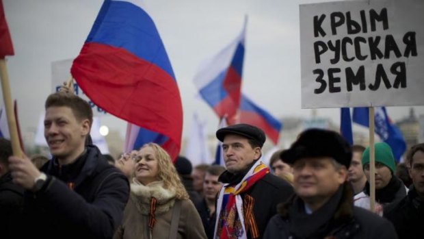 Nationalists ... Pro-Putin demonstrators with St. George ribbons hold Russian national flags and posters reading 'Crimea is Russian land!' as they gather towards to Red Square in Moscow.