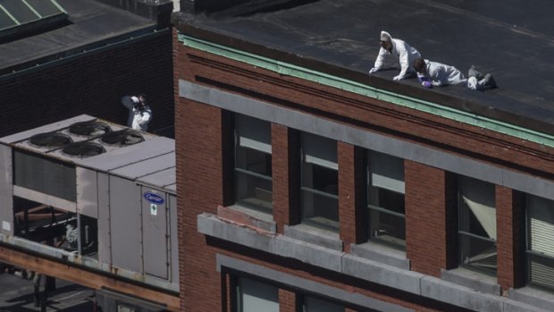 No stone unturned ... Investigators inspect the roof of a building above the bomb blast site in Boston.