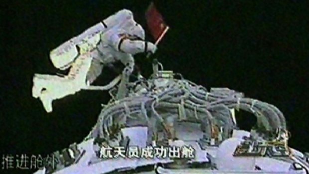Zhai Zhigang waves the Chinese flag during the broadcast.