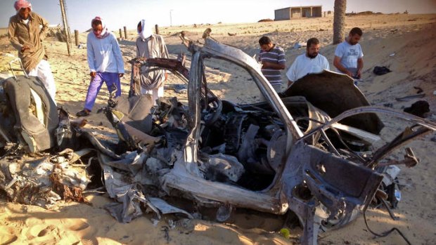 Egyptians gather near a damaged car bomb that detonated before reaching the intended target killing three passengers in El-Arish in Egypt's Sinai peninsula.