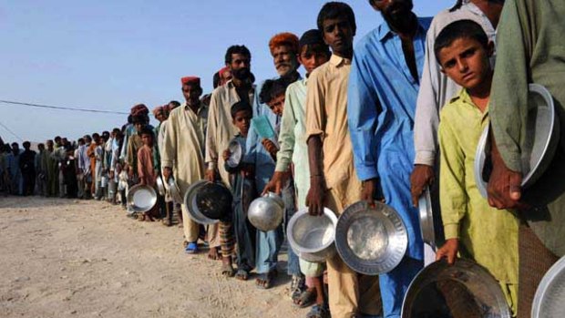 Pakistanis stand in a queue to get relief food at a camp in Sukkur.