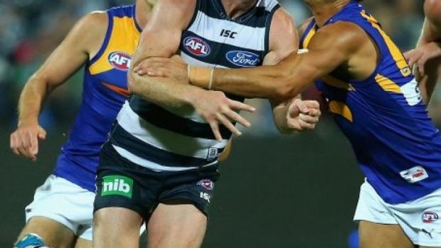 Steve Johnson of the Cats handballs whilst being tackled by Sharrod Wellingham of the Eagles.