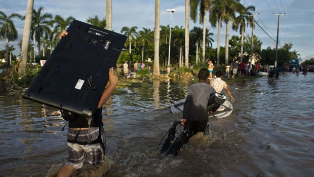Looters carry goods from a supermarket in Acapulco, Mexico as heavy rains hit the country.