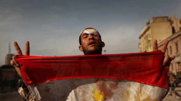 An anti-government demonstrator holds a bloodied Egyptian flag after a deadly battle with regime supporters in Tahrir Square, Cairo.