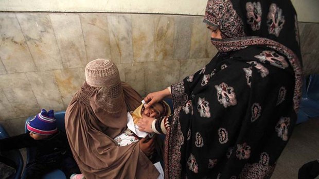 A polio worker gives vaccine drops to a child at a hospital in Peshawar.