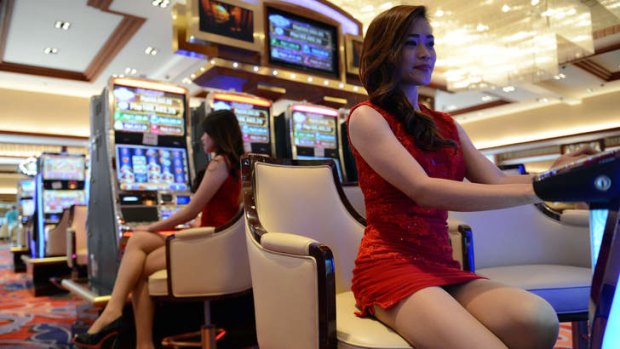 Models at Solaire Manila Resorts and Casino pose for photo next to gaming machines.