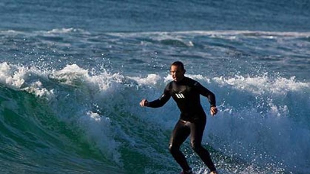 Opposition leader Tony Abbott rides a wave at Manly at 7.23am today.