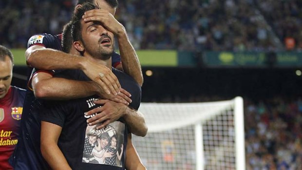 Barcelona's David Villa celebrates his goal against Real Sociedad with teammates as he wears a T-shirt with a picture of his family.