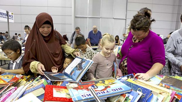 Lugman Abdurro'uf, 7, Indah Suryani, Luthfi Abdurrosyid, 4, and Ridhwan Abdurrohman, 10, Lola Gosper-Currey, 7, and Ruth Hillier browse through the thousands of books at the Lifeline Bookfest at the Brisbane Convention Centre.
