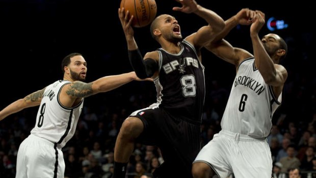 Patty Mills goes up between Brooklyn Nets players Alan Anderson (r) and Deron Williams.