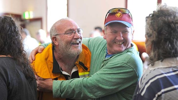 Two men embrace at a community meeting at Snake Valley Community hall.