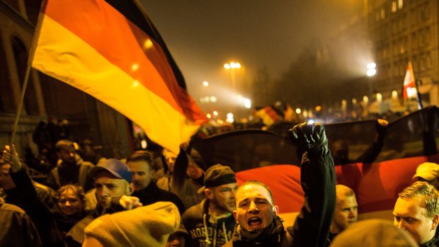 A supporter of the PEGIDA movement holds a flag while supporters gather for a march in their first Berlin demonstration, which they have dubbed "Baergida," on January 5 in Berlin. 