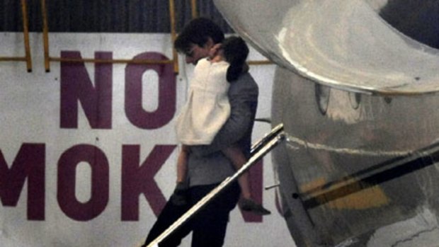 Tom Cruise carries daughter Suri from his private jet at Essendon Airport.