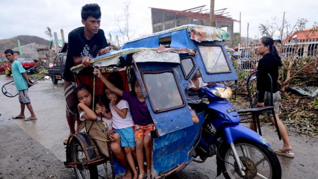 Children pack a motorbike's sidecar as they travel along a street in an area devastated by Typhoon Haiyan in Leyte, Philippines.