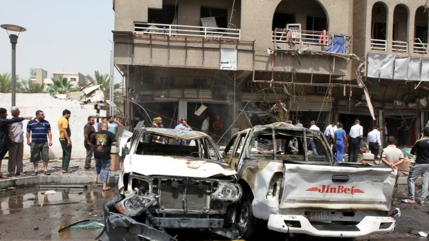 Iraq security forces and onlookers gather at the site of a car bomb attack in Baghdad on May 9, 2015, which killed seven civilians and wounded 14 others.