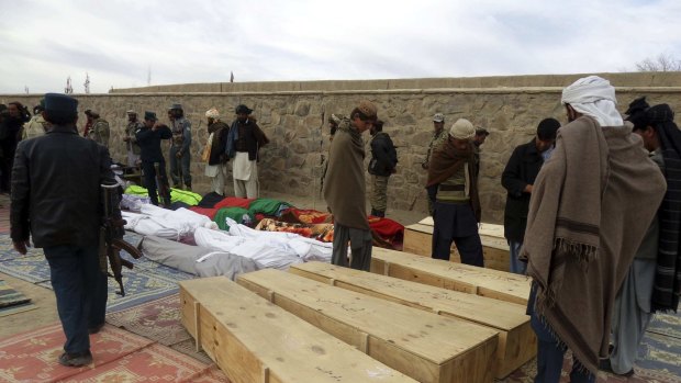 Afghan men gather around the bodies of victims of Sunday's suicide attack at a volleyball match in Yahya Khail district.