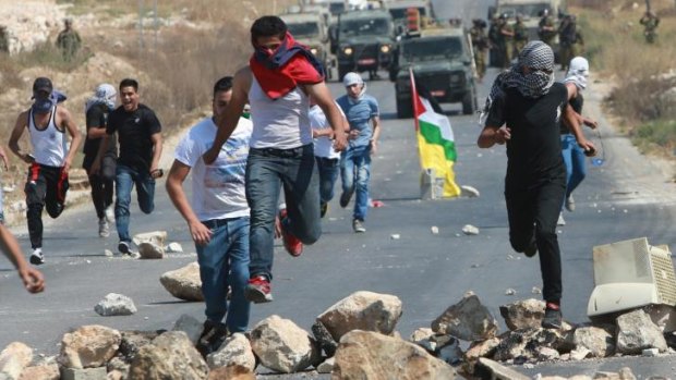 Palestinian protesters run for cover as Israeli soldiers fire rubber bullets after the demonstration.