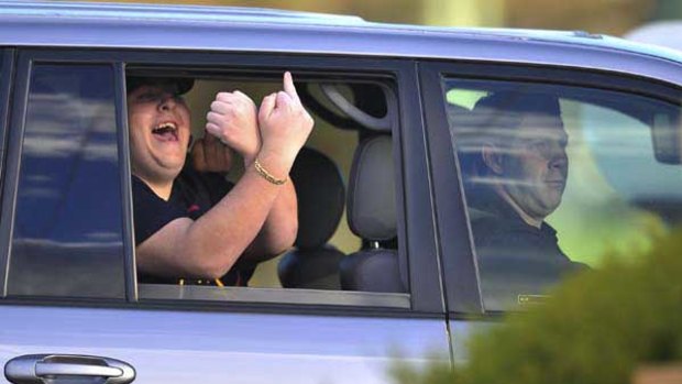 Omar Chaouk mocks photographers as he is driven from Barwon prison.