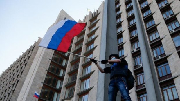 Tensions: A masked activist waves a Russian flag in front of the regional administration building in Donetsk.