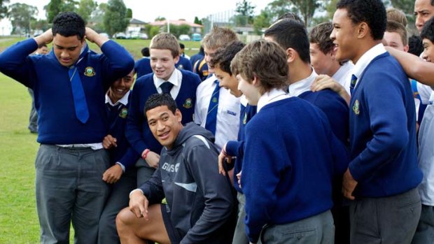 The pied piper of AFL ... Israel Folau is surrounded by students of Westfield Sports High School in Fairfield yesterday. Folau also attended the school, but as a budding league player.