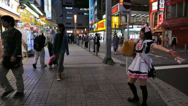A Japanese woman dressed as a French maid promotes a maid cafe in Akihabara.