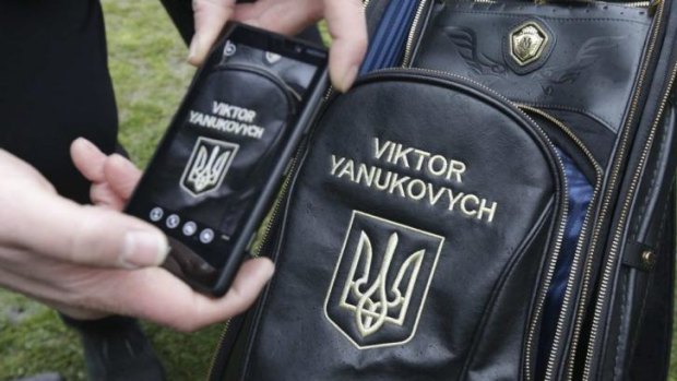 Swinging freely ... A man takes a photo of ousted Ukraine president Viktor Yanukovich's personalised golf bag.