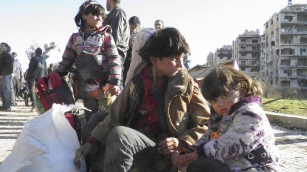 Evacuation: Children sit with their belongings as they wait to leave Homs.