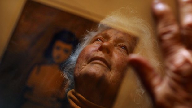 Betty Burstall photographed in 2005 with a painting by artist Charles Blackman, which he gave her 40 years earlier after she helped him out by paying for his dinner.