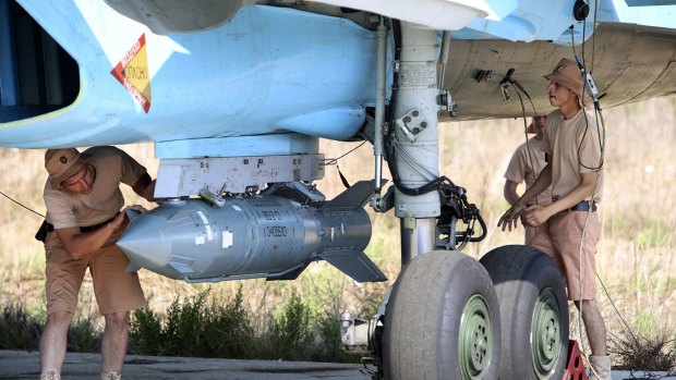 Russian military support crew attach a satellite-guided bomb to a jet fighter in Syria.