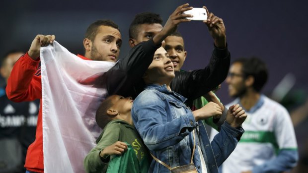 Algeria supporters take a photograph on the pitch after the friendly between their nation and Romania.