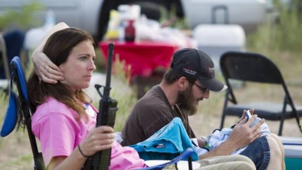 Chris Shelton of Las Vegas interacts with his one-week-old son as his mother Shelley Shelton holds his rifle during a Bundy family "Patriot Party" in Nevada.