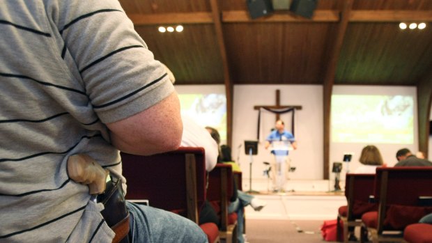 A man with a firearm listens to Pastor Ken Pagano during the "Open Carry Celebration" at New Bethel Church in Louisville, Kentucky.