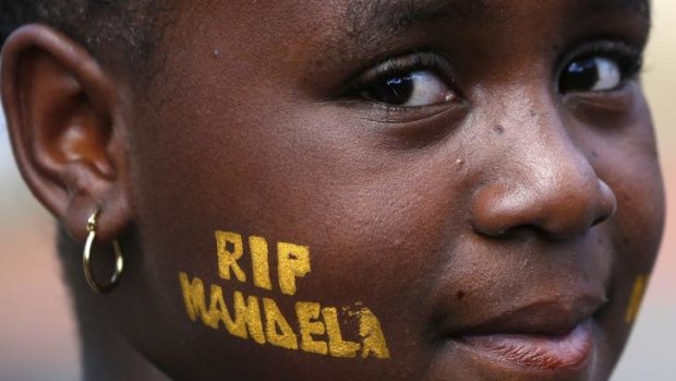 A girl displays the text 'RIP Mandela' on her cheek while waiting with her family to pay tribute to former South African President Nelson Mandela in Pretoria.